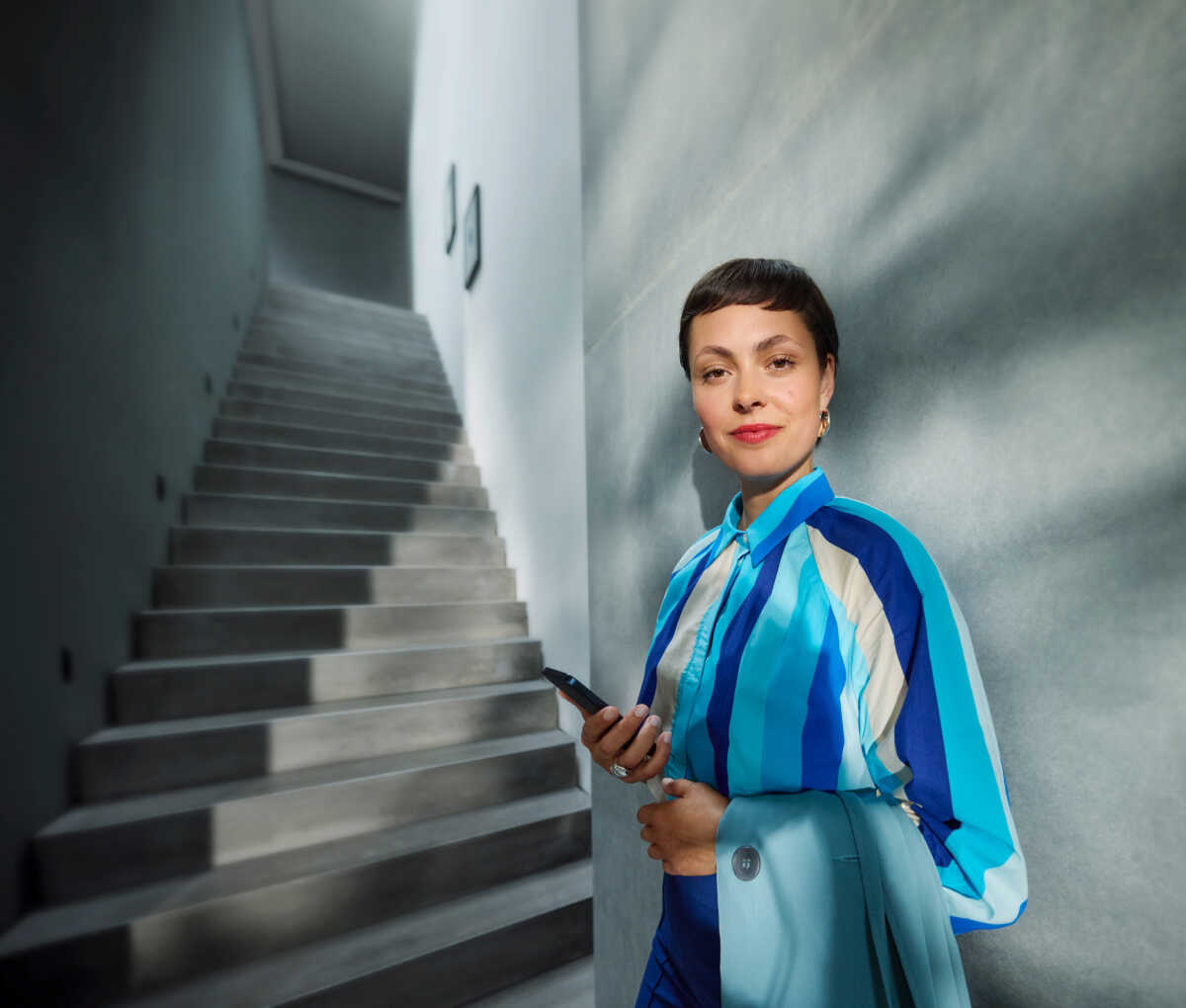 Frau in blau weiß gestreiften Kleid steht vor einer Betontreppe