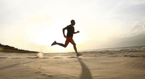 Mann joggt bei Sonnenuntergang am Strand