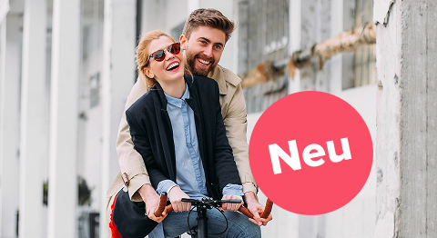 Mann und Frau sitzen zusammen auf einem Fahrrad und lachen